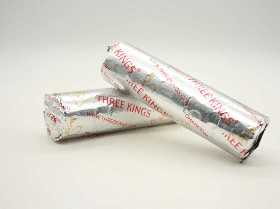 Dvije aluminijske folije s natpisom 'THREE KINGS' koje sadrže čađene ugljen tablete, postavljene na bijelu pozadinu.