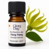 Bočica s eteričnim uljem Ylang Ylang marke Glory Day, uz cvijet ylang-ylang u pozadini.